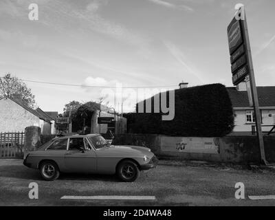 Ein klassischer MGB GT ruht vor einer verlassenen Tankstelle Stockfoto