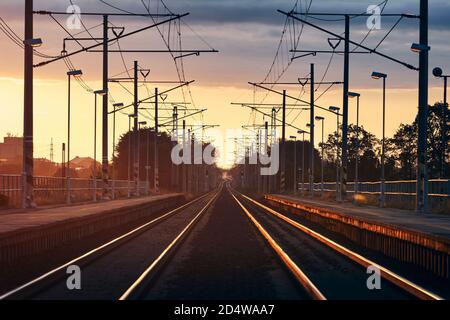 Eisenbahn bei schönem Sonnenaufgang. Abnehmende Perspektive von zwei leeren Gleisen im Bahnhof. Stockfoto