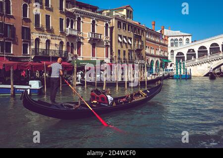 Gondoliere auf einer Gondel, die in Richtung Rialtobrücke auf dem Canal Grande in Venedig rudert. Stockfoto