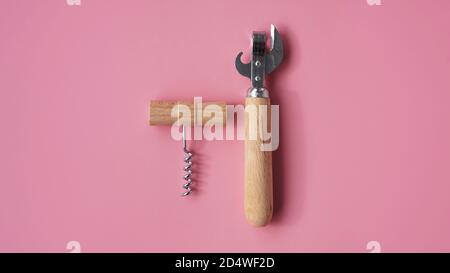 Korkenzieher aus Holz und Zinnöffner auf rosa Hintergrund Stockfoto