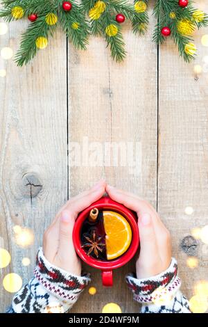 Hände halten rote Keramik-Tasse mit Glühwein, Holzhintergrund mit Kopieplatz. Stockfoto