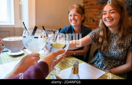 Gin und Tonic Toast - Trinken im Pub - Familien-Toast mit Gin und Tonics und Gin und Ingwer Ale und Tasse Kaffee für Fahrer in Pub - England, UK Stockfoto