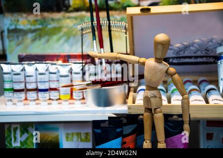 Hölzerne Zeichenpuppe vor vielen Farbtuben in Ein Kunstgeschäft Stockfoto
