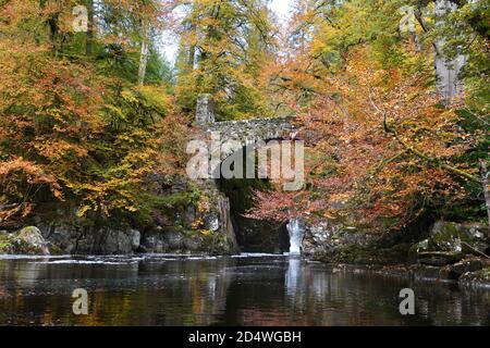 Dunkeld, Schottland, Großbritannien. Oktober 2020. Gebrochene Wolken ließen kurze Sonnenstrahlen die Herbstbaumfarben am Hermitage Wasserfall am Fluss Brann bei Dunkeld erleuchten. Stockfoto