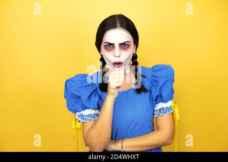 Frau trägt ein gruseliges Puppe halloween Kostüm auf gelbem Hintergrund Husten Stockfoto