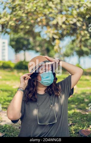 Vertikale Bild einer Frau in einem Hut und medizinische Maske genießen den Tag. Neuer Normalwert. Speicherplatz kopieren Stockfoto