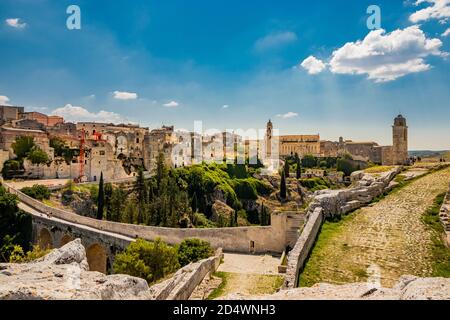 Gravina in Apulien, Italien. Die Steinbrücke, das antike Aquädukt und das Viadukt. Über das Tal die Skyline der Stadt mit ihren Häusern und Gebäuden und Stockfoto