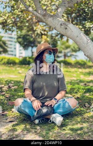 Junge Frau genießt die Natur und schützt sich mit einer medizinischen Maske. Neuer Normalwert Stockfoto