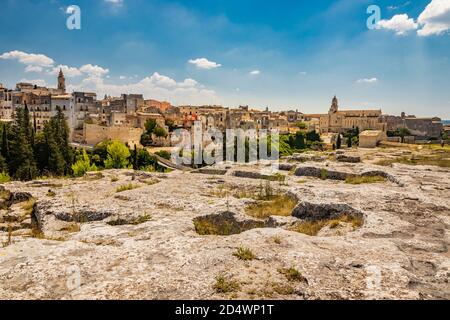 Gravina in Apulien, Italien. Der archäologische Park von Botromagno auf dem Gipfel des Hügels mit Höhlenhäusern und Höhlenkirchen. Die Skyline der Stadt wit Stockfoto