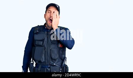 Junger gutaussehender Mann mit Polizeiuniform gähnend müde Abdeckung halb Gesicht, Auge und Mund mit Hand. Gesicht schmerzt in Schmerzen. Stockfoto