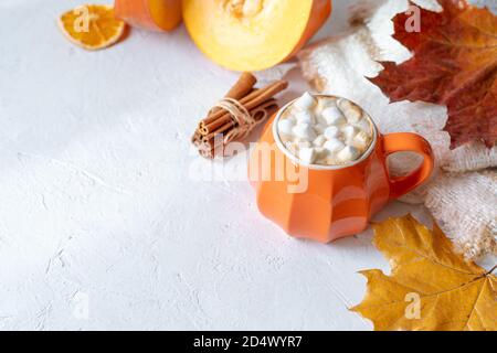 Komposition mit orangefarbenem Kürbis-Stil Tasse Kaffee mit Marshmallows und Herbstdeko, gefallenen Blättern, gemütlichem Pullover auf weißem Hintergrund. Stockfoto