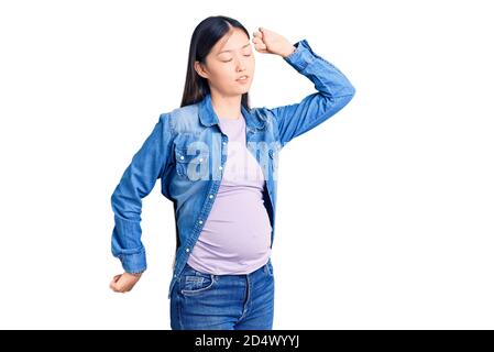 Junge schöne chinesische Frau schwanger erwartet Baby Stretching zurück, müde und entspannt, schläfrig und Gähnen für den frühen Morgen Stockfoto