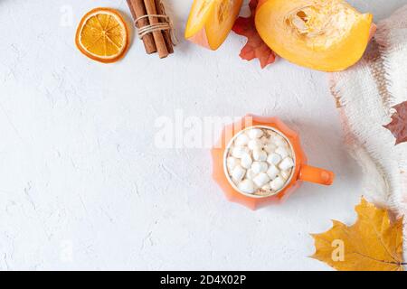 Komposition mit orangefarbenem Kürbis-Stil Tasse Kaffee mit Marshmallows und Herbstdeko, gefallenen Blättern, gemütlichem Pullover auf weißem Hintergrund. Stockfoto