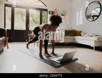 Afroamerikanische Teenager üben Yoga Flow beobachten Video auf Laptop In moderner Lounge Stockfoto