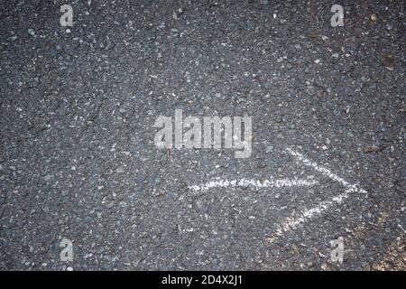 Weißes Pfeilzeichen in Kreide auf dem Asphalt gezeichnet Stockfoto