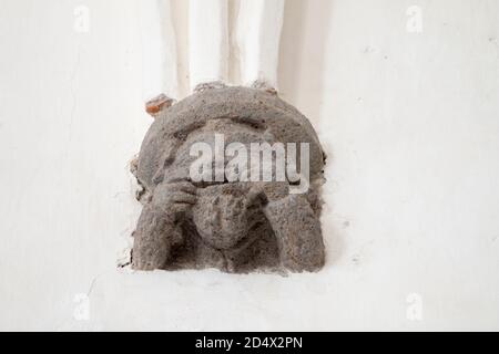 Grimacing Gesicht Skulptur gezogen Mund von Fingern. Stützkorbel unter dem gotischen Bogen in der UNESCO-Weltkulturerbe Unitarier Wehrkirche. Stockfoto