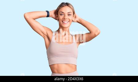 Schöne kaukasische Frau trägt Sportkleidung entspannend und Stretching, Arme und Hände hinter Kopf und Hals lächelnd glücklich Stockfoto