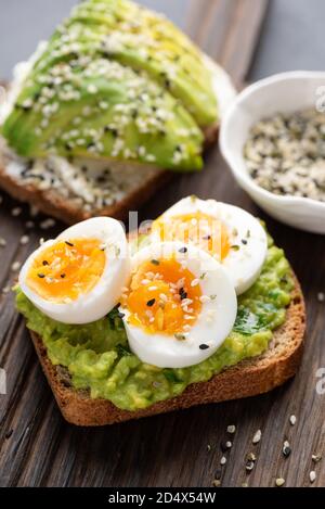 Vollkorntoast mit Avocado und Ei auf Holztisch. Gesundes Frühstück Mittagessen oder Snack Avocado Bruschetta Stockfoto