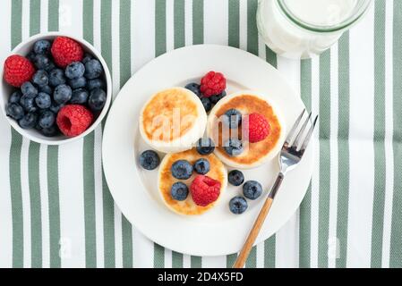 Hüttenkäse Fritten mit Sommerbeeren Heidelbeeren und Himbeeren. Syrniki, Käsepfannkuchen Stockfoto