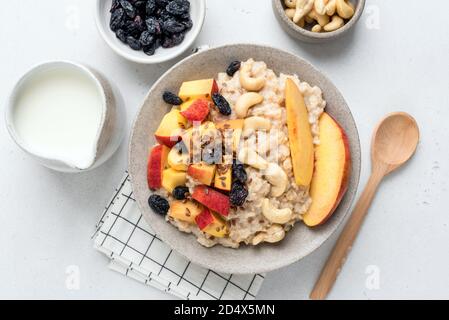 Haferbrei Schüssel mit Früchten und Nüssen. Pfirsich Rosinen Cashew und Leinsamen Haferbrei Haferbrei. Gesundes Frühstück Stockfoto