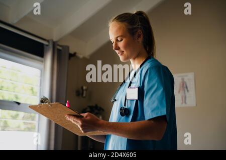 Kaukasische weibliche Krankenschwester schriftlich Übungen für Patienten stehen in der Klinik Stockfoto