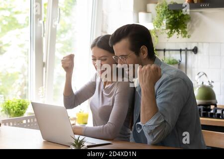 Überglücklich junge verheiratete Paar macht ja Geste, Blick auf Computer. Stockfoto