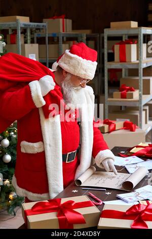 Weihnachtsmann mit Sack Tasche mit Geschenken Geschenke Lesen Wunschliste. Stockfoto