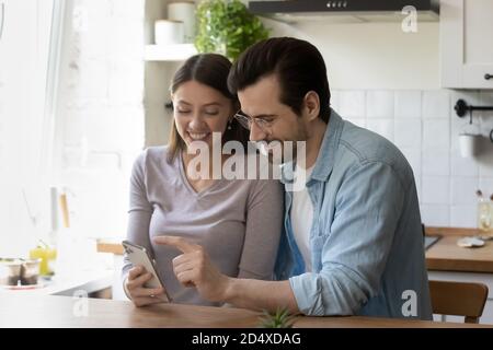 Hübsche junge Frau zeigt lustige mobile App für den Mann. Stockfoto