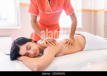 Junge Frau haben medizinische Erholung Massage. Nahaufnahme einer Frau, die sich während der Rücken- und Nackenmassage entspannt Stockfoto