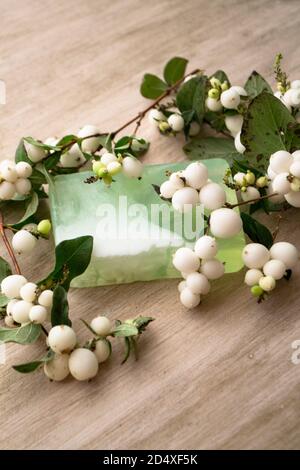 Handgemachte Seife mit weißen Beeren auf einem Holz umweltfreundliche Seifenschale zwischen Muscheln. Stilvolle rustikalen Hintergrund. Vertikales Bild Stockfoto