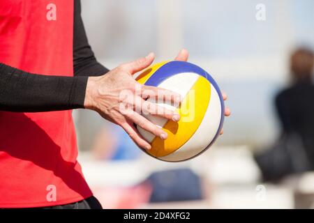Beachvolleyballspieler, der den Ball während eines Beachvolleyballturniers in Rom in Italien serviert. Spielen Sie den Sommer. Einen Beachvolleyball in den Händen halten. Stockfoto