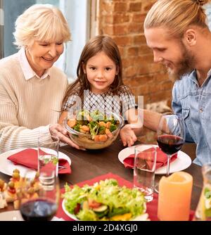 Fröhliche Familie sitzt am festlichen Tisch mit gesunden Lebensmitteln Stockfoto