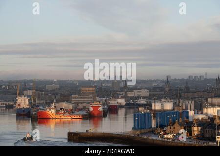 Frühmorgens Sonnenschein auf den Versorgungsbooten und Lagertanks im Hafen von Aberdeen, mit Blick auf die Stadt Stockfoto