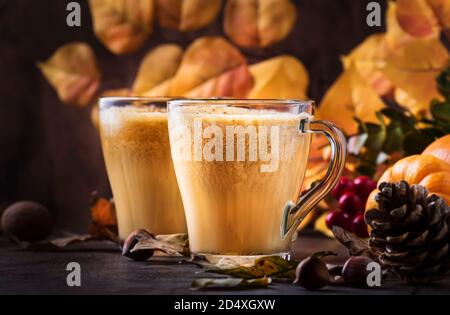 Kürbis gewürzter Latte oder Kaffee in Glas Tasse auf Vintage Holztisch. Heißes Getränk im Herbst oder Winter Stockfoto