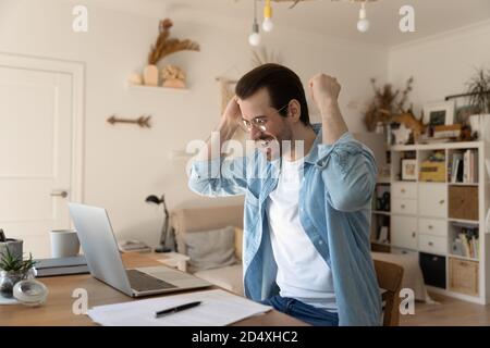 Überglücklich junger Mann, der die Arme in der Luft hebt und eine Geste macht. Stockfoto