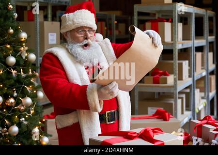 Schockiert Weihnachtsmann trägt Kostüm Lesung Wunschliste stehen in der Werkstatt. Stockfoto