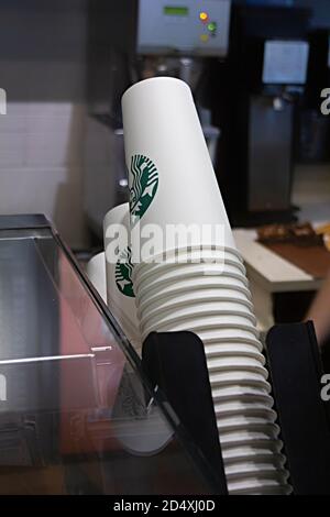 Saint-Petersburg, Russland - 03. OKTOBER 2020 Starbucks Einweg-Pappbecher stehen in der Nähe einer Kaffeemaschine und Kasse in einem Starbucks Café Stockfoto
