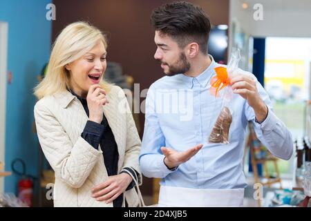 Staunende hübsche Frau, die bei der Bäckerei auf Tassenkuchen schaut Stockfoto