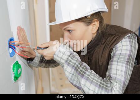 Elektrikerin, die an der Steckdose arbeitet Stockfoto