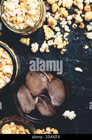 Eis Cola und Karamell Popcorn, ungesunde Speisen und Getränke, schwarzer Tisch, Draufsicht Stockfoto