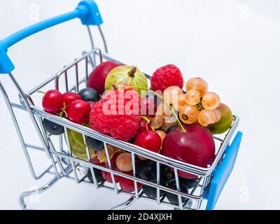 Mini-Lebensmittelkarren mit frischen Vitamin-Beeren auf weißem Hintergrund isoliert gefüllt. Stockfoto