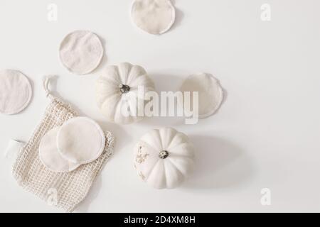 Bio-Bio-Baumwolle wiederverwendbare runde Pads für Make-up Entfernung mit Kürbissen und gestrickte Tasche auf weißem Tischhintergrund. Zero Waste Konzept. Nachhaltig Stockfoto