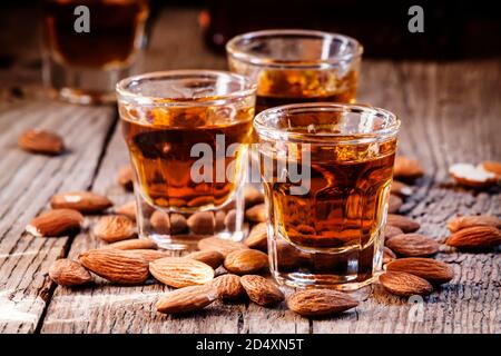 Italienischer Amaretto Likör mit trockenen Mandeln auf dem alten Holzhintergrund, selektiver Fokus Stockfoto