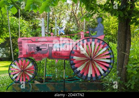 Alte rot, schwarz und weiß gestickte Leinwand Reproduktion eines McCormick Farmall Bauernhof Traktor im Garten. Stockfoto