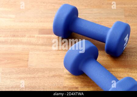 Zwei Paar blaue Fitness-Hanteln auf Holzboden, Konzept gesunde Lebensweise, Sport und Ernährung. Sportausrüstung. Stockfoto