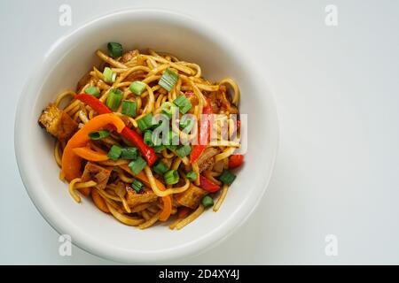 Draufsicht auf gebratenen Tofu und Gemüse Gericht auf Eine weiße Platte und weißer Hintergrund Stockfoto