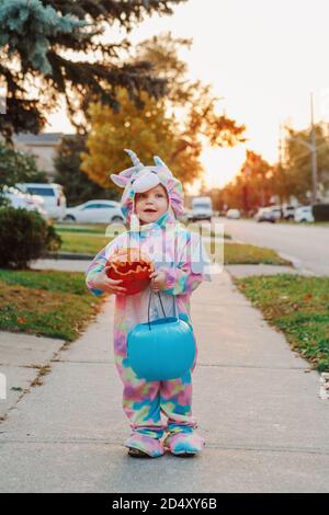 Trick or Treat. Happy Baby Kleinkind mit rotem Kürbis und Korb gehen zu Trick oder zu behandeln auf Halloween-Urlaub. Niedliches Kind Kind im Party-Kostüm gehen zu Stockfoto