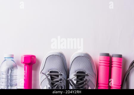 Paar Sportschuhe, Kopfhörer, Hantel und Wasserflasche auf weißem Hintergrund, Grau Sneaker und Zubehör Geräte in Fitness-STUDIO, gesundes Training Stockfoto