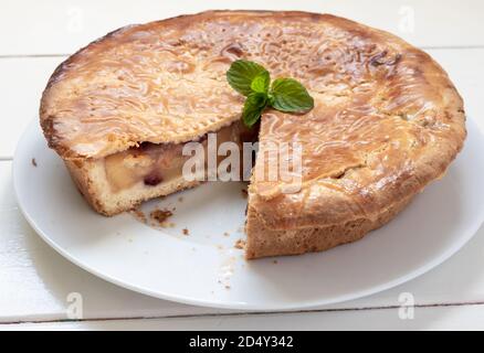 Traditionelle hausgemachte Apfelkuchen mit Preiselbeeren. Komplette Kuchen auf einem weißen Holztisch Stockfoto