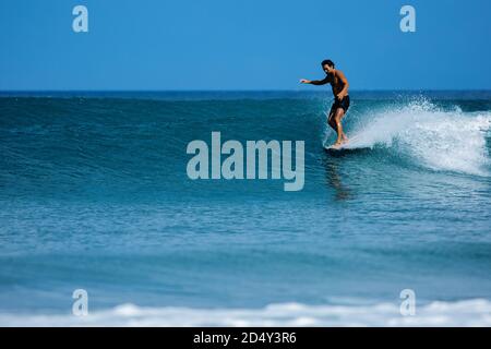 koreanischer Surfer reitet ein Longboard auf blauen Wellen.Foto in hoher Qualität Stockfoto